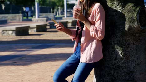 Woman-using-mobile-phone-while-having-juice-in-park-4k