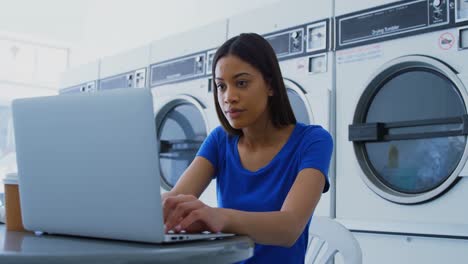Woman-using-laptop-at-laundromat-4k