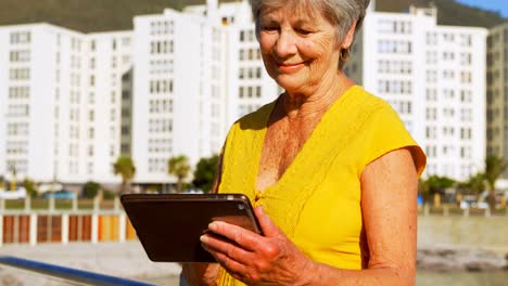 Mujer-Mayor-Usando-Tableta-Digital-En-El-Paseo-Marítimo-4k