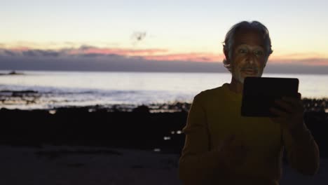 Senior-man-using-digital-tablet-on-the-beach-4k