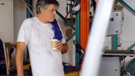 Male-mechanic-having-coffee-in-garage-4k