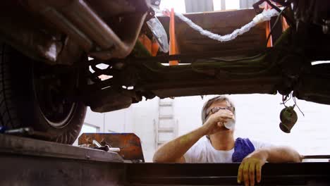 Male-mechanic-having-coffee-while-servicing-a-car-4k
