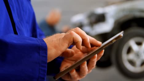 Mechanic-using-digital-tablet-in-garage-4k