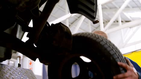 Mechanic-fixing-car-wheel-in-garage-4k