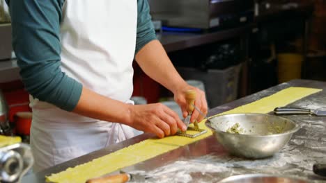 Male-and-female-baker-using-ravioli-stamp-on-pasta-dough-4k