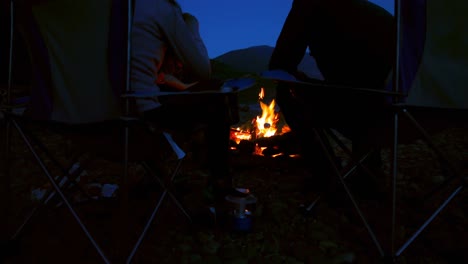 Group-of-hikers-roasting-marshmallows-near-campfire-4k