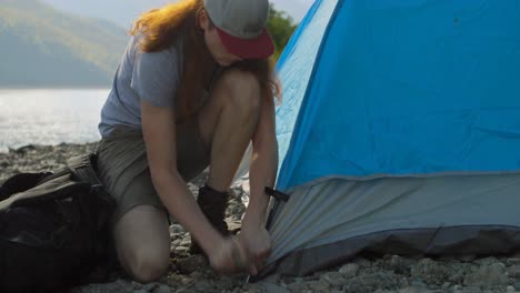 Man-setting-up-tent-near-riverside-4k