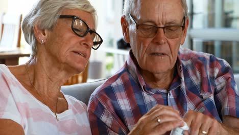 Senior-couple-discussing-medication-on-sofa-4k