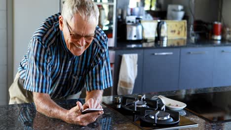 Senior-man-using-mobile-phone-in-kitchen-4k