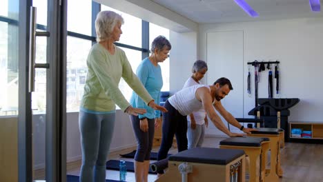 Trainer-assisting-senior-women-in-performing-yoga-4k