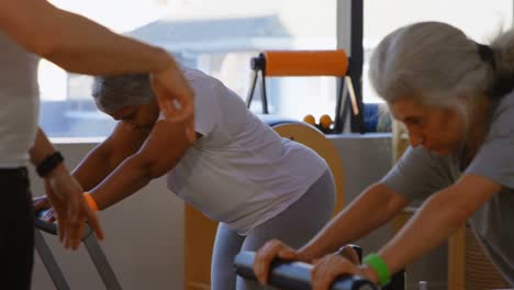 Trainer-assisting-senior-women-while-performing-yoga-4k