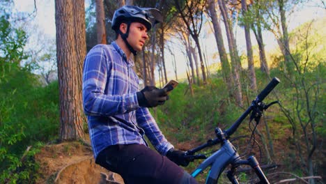 Man-using-mobile-phone-while-sitting-on-cycle-4k
