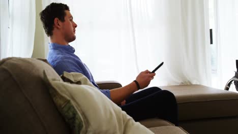 Disabled-man-watching-television-on-sofa-4k
