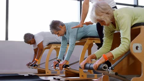 Trainer-assisting-senior-women-to-exercise-4k