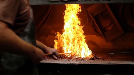 Blacksmith-heating-metal-rod-in-fire-4k