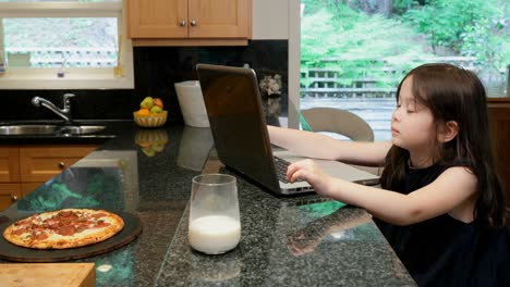 Little-girl-using-laptop-in-kitchen-at-home-4k