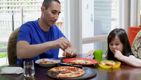 Father-cutting-a-slice-of-pizza-for-his-daughter-