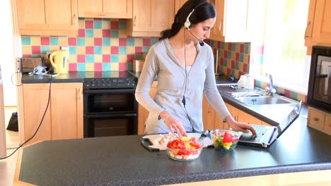 Modern-woman-preparing-a-salad-and-communicating-on-internet