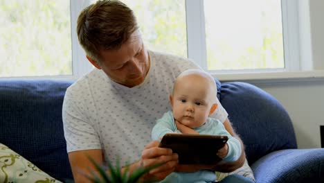 Vater-Und-Kleiner-Junge-Nutzen-Digitales-Tablet-Im-Wohnzimmer-4k