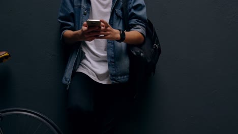 Man-using-mobile-phone-while-leaning-against-wall-4k