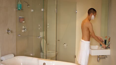 Man-applying-shaving-cream-on-his-face-at-bathroom-4k