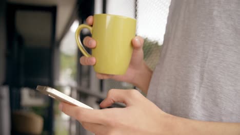 Man-having-coffee-while-using-mobile-phone-at-home-4k