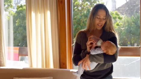 Mother-feeding-milk-to-her-baby-boy-in-living-room-4k