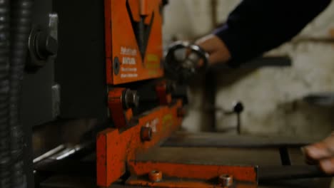 Metalsmith-operating-a-machine-in-workshop-4k