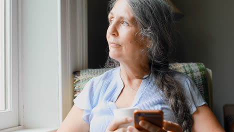 Senior-woman-having-coffee-while-using-mobile-phone-4k
