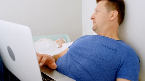 Baby-Schläft,-Während-Der-Vater-Im-Schlafzimmer-Einen-Laptop-Benutzt-4k