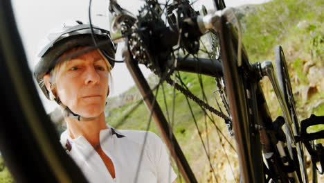 Ciclista-Senior-Revisando-Bicicleta-En-El-Campo-4k