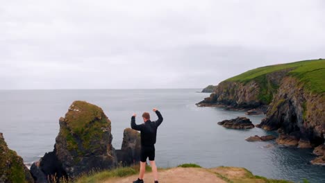 Man-walking-on-cliff-with-his-hands-spread-and-arms-up-4k