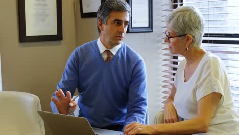 Optometrist-discussing-over-laptop-with-patient-4k