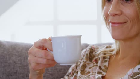 Woman-having-coffee-on-sofa-at-home-4k