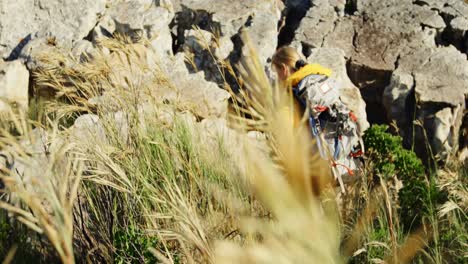 Senior-woman-climbing-rock-at-countryside-4k