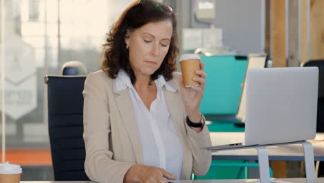 Mujer-De-Negocios-Tomando-Café-Mientras-Usa-El-Teléfono-Móvil-En-El-Escritorio-4k