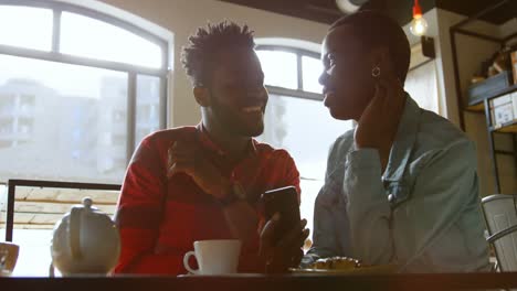 Couple-using-mobile-phone-in-cafe-4k
