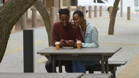 Couple-using-mobile-phone-in-outdoor-cafe-4k