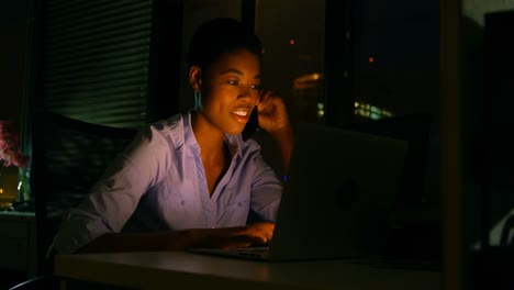 Weibliche-Führungskraft-Benutzt-Laptop,-Während-Sie-Am-Schreibtisch-Mit-Dem-Mobiltelefon-Telefoniert-4k