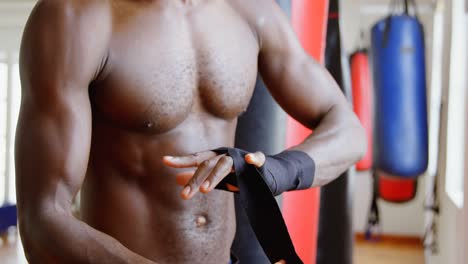 Male-boxer-wearing-hand-wrap-in-fitness-studio-4k