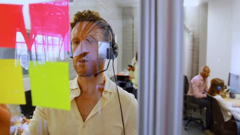 Male-executive-talking-on-headset-while-looking-sticky-note-4k