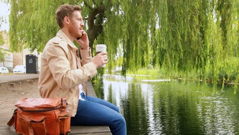 Man-having-coffee-while-talking-on-mobile-phone-4k