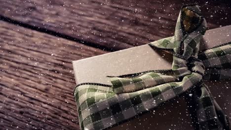 Fallender-Schnee-Mit-Weihnachtsgeschenk-Auf-Holz