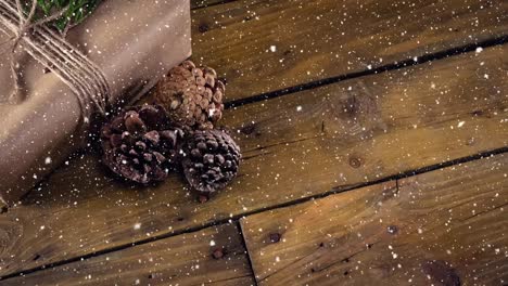 Fallender-Schnee-Mit-Weihnachtlicher-Tannenzapfendekoration-Auf-Holz