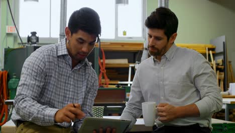 Engineers-discussing-over-digital-tablet-in-workshop-4k