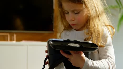Adorable-girl-looking-at-virtual-reality-headset-at-home-4k