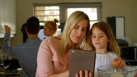 Mother-and-daughter-using-digital-tablet-while-preparing-food-4k
