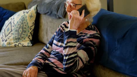 Senior-woman-talking-on-mobile-phone-in-living-room-4k
