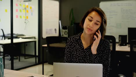 Businesswoman-talking-on-mobile-phone-at-desk-4k