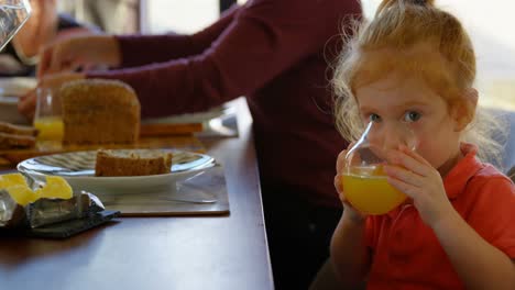 Cute-little-boy-drinking-orange-juice-at-dining-table-4k